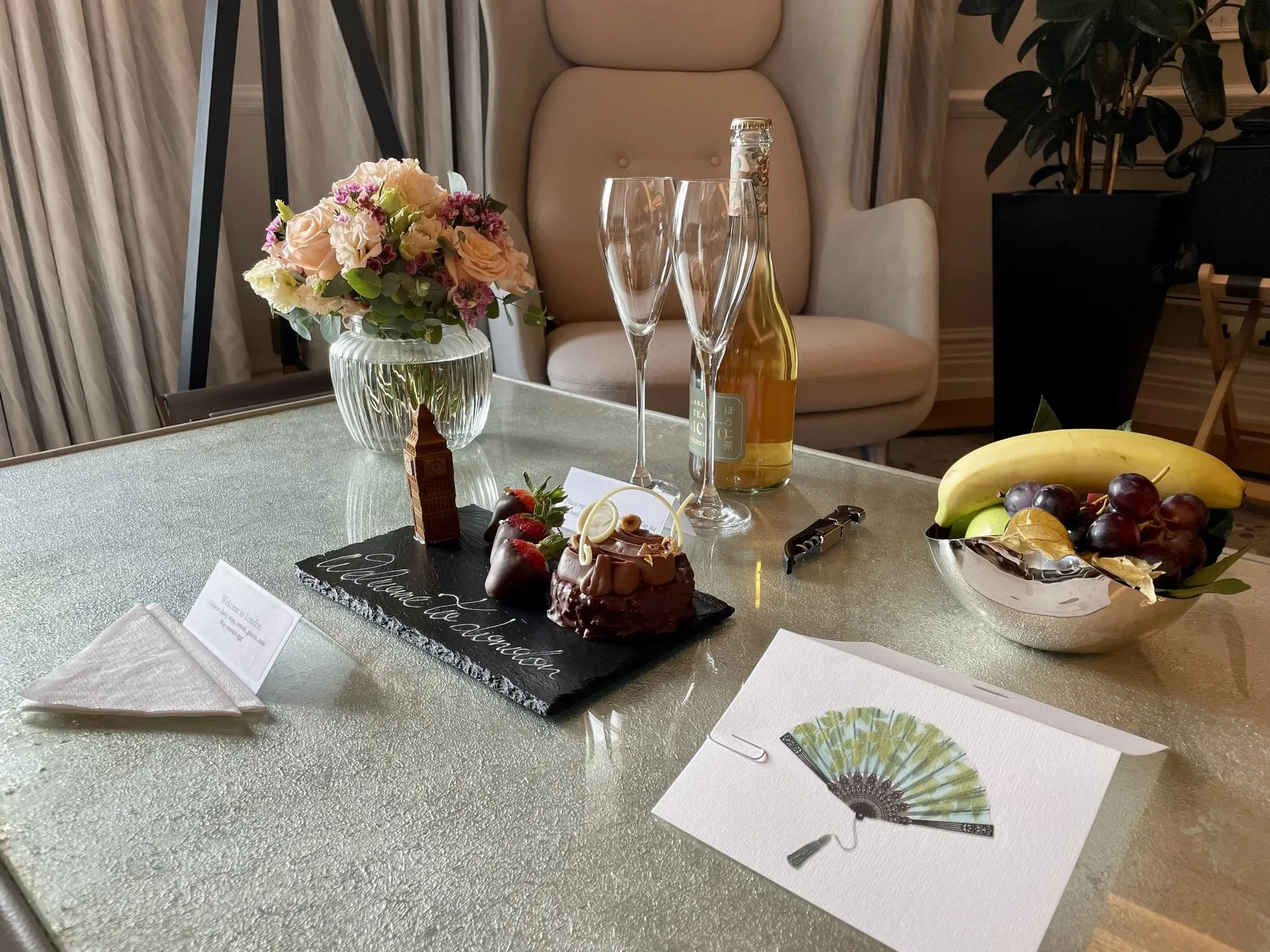 A hotel welcome amenity: champagne, flowers, chocolates and fruit on a marble table